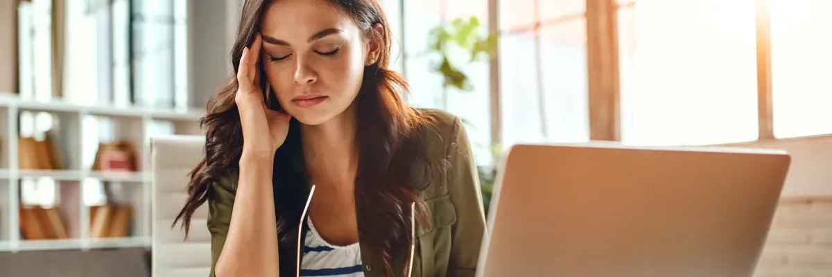 Woman with stress headache; Mattress Direct explains how managing stress is vital for achieving restorative sleep.